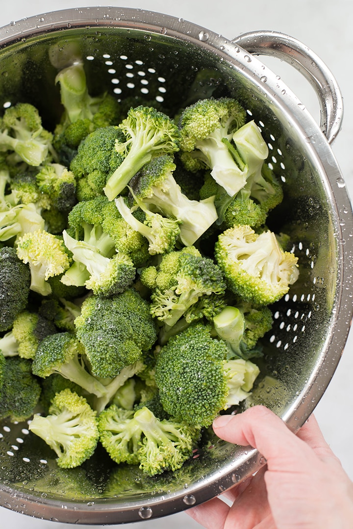 Washed broccoli florets in a colander.
