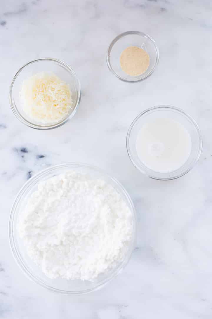 Separate ingredients for Homemade Alfredo Sauce including cottage cheese, parmesan, garlic powder, and almond milk.