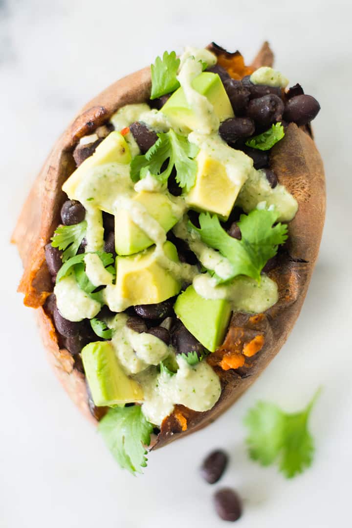 Close up view from the top of Chipotle Black Beans Stuffed Baked Potato which is garnished with avocado and black beans.