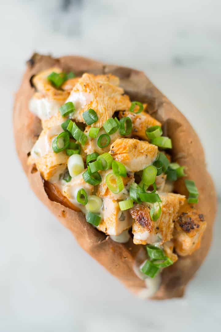 Top view of Buffalo Chicken baked Sweet Potato garnished with scallions, a carb that is good for you