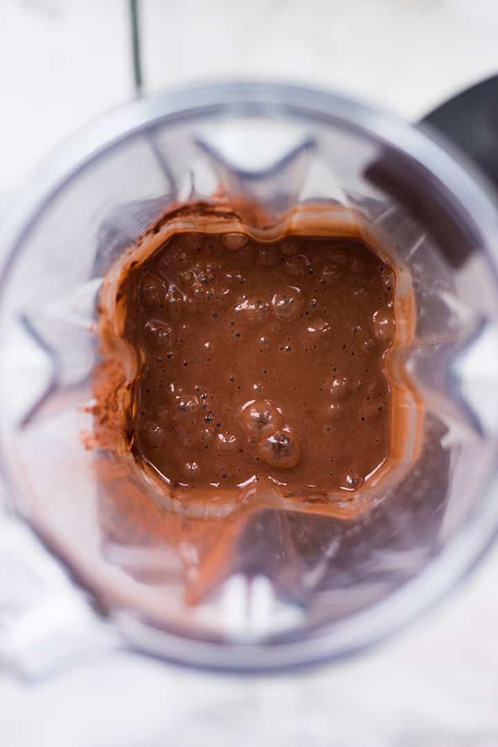 Overhead view of a Vitamix filled with blended ingredients for chocolate muffins.