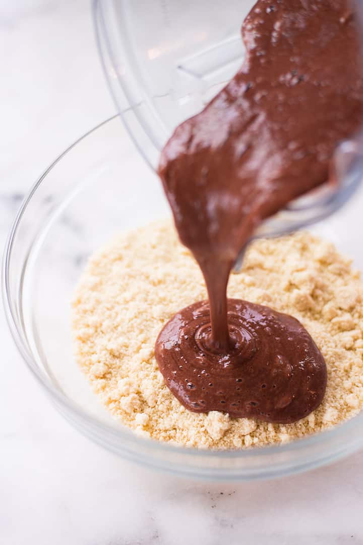 Pouring the chocolate-banana mixture over almond flour to finalize the chocolate muffin batter.