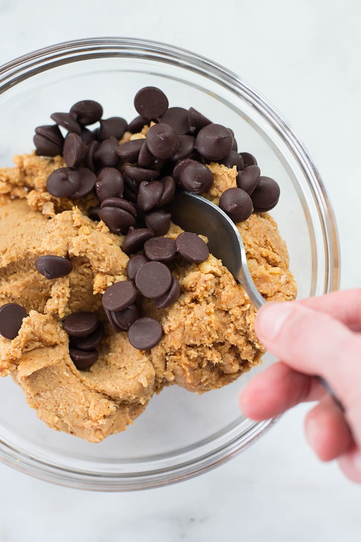 Mixing dark chocolate chips with edible cookie dough in a mixing bowl.
