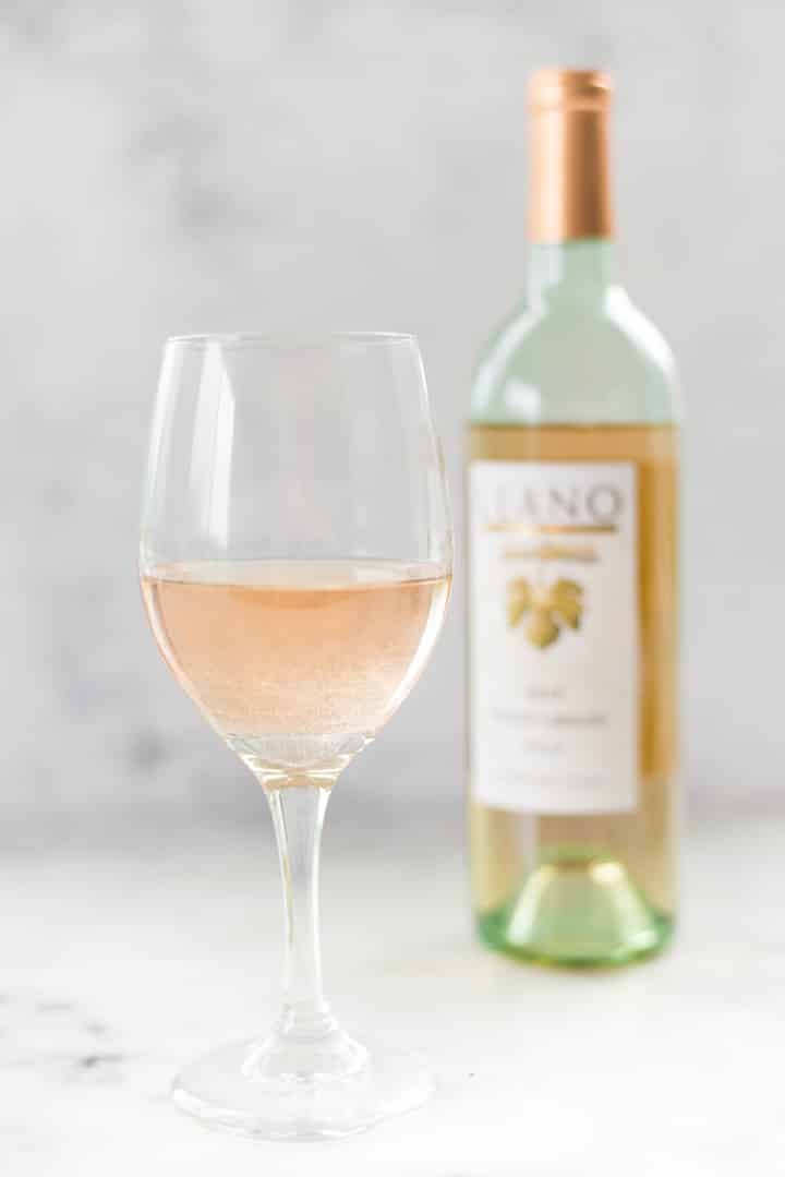 A glass of Llano Estacado Pinot Grigio ine next to the bottle of Llano Estacado Pinot Grigio.