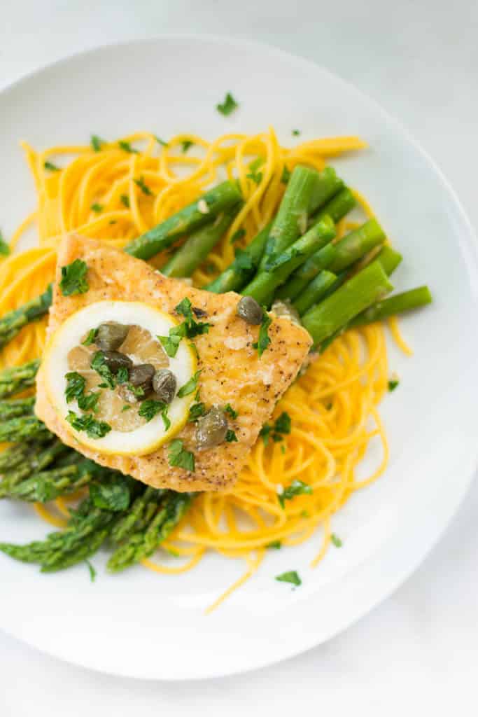 Overhead view of Healthy Halibut Piccata With Asparagus, served on a white plate and garnished with lemon, ideal for an Intermittent Fasting meal.