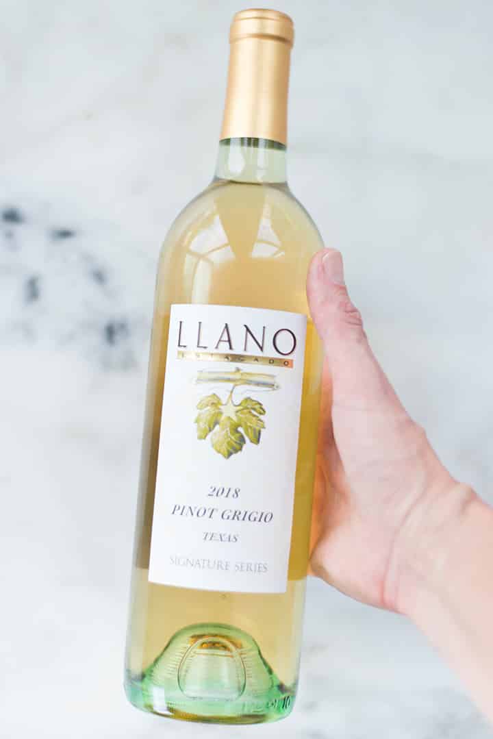 Lacey holding a bottle of Llano Estacado Pinot Grigio white wine, the wine used for making halibut picatta.