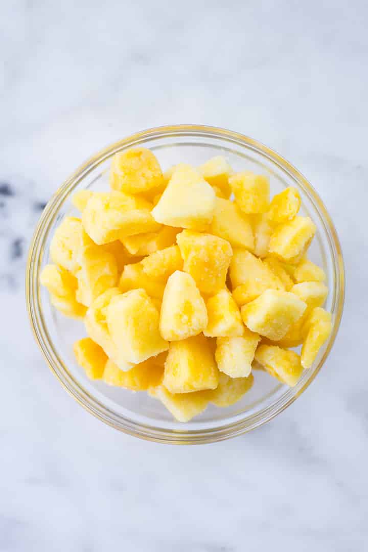 View from the top of a mixing bowl filled with frozen pineapple cubes.