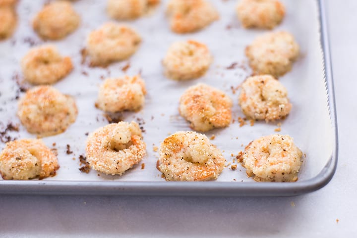 Close-up view of rimmed baking sheet with breaded shrimp that has been cooked to show the shrimp is cooked through and no longer translucent.