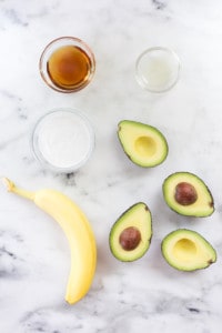 Simple ingredients for the avocado ice cream, including avocado, banana, coconut milk, raw honey, and fresh lemon juice.