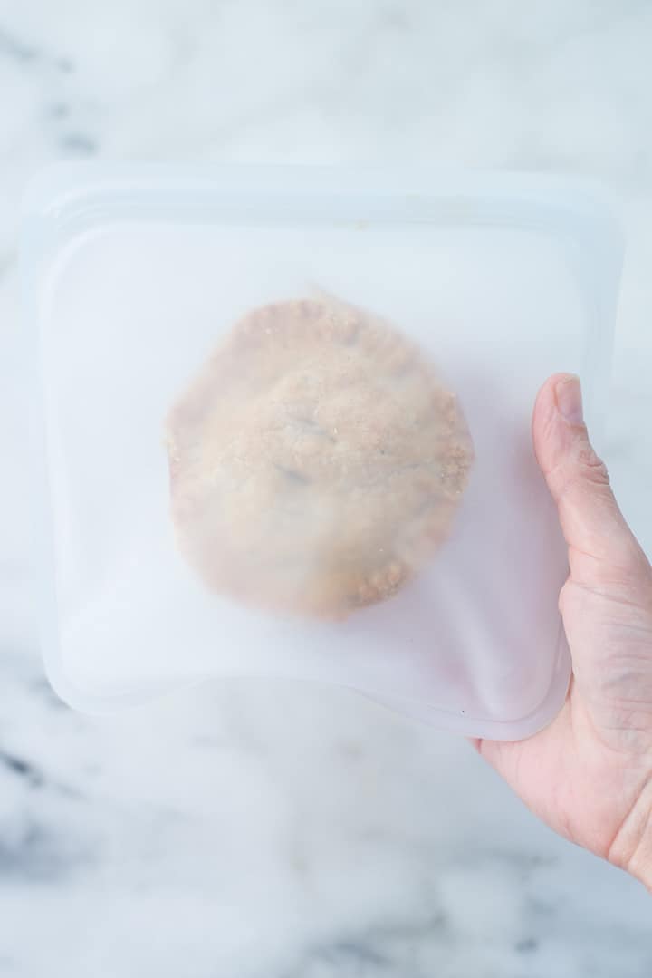 Hand holding a mini freezer chicken pot pie in a re-usable storage freezer bag to show how to freeze.