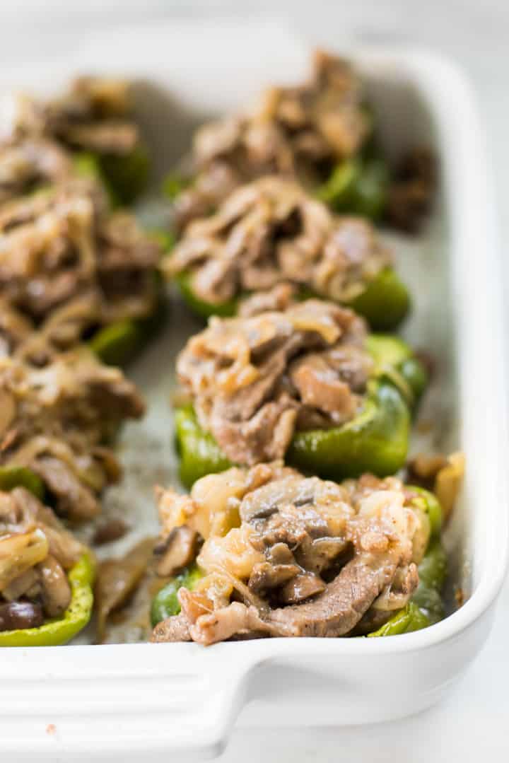Keto Philly Cheesesteak Stuffed Peppers with steak, mushrooms, and cheese in a white glass casserole dish, ready to serve