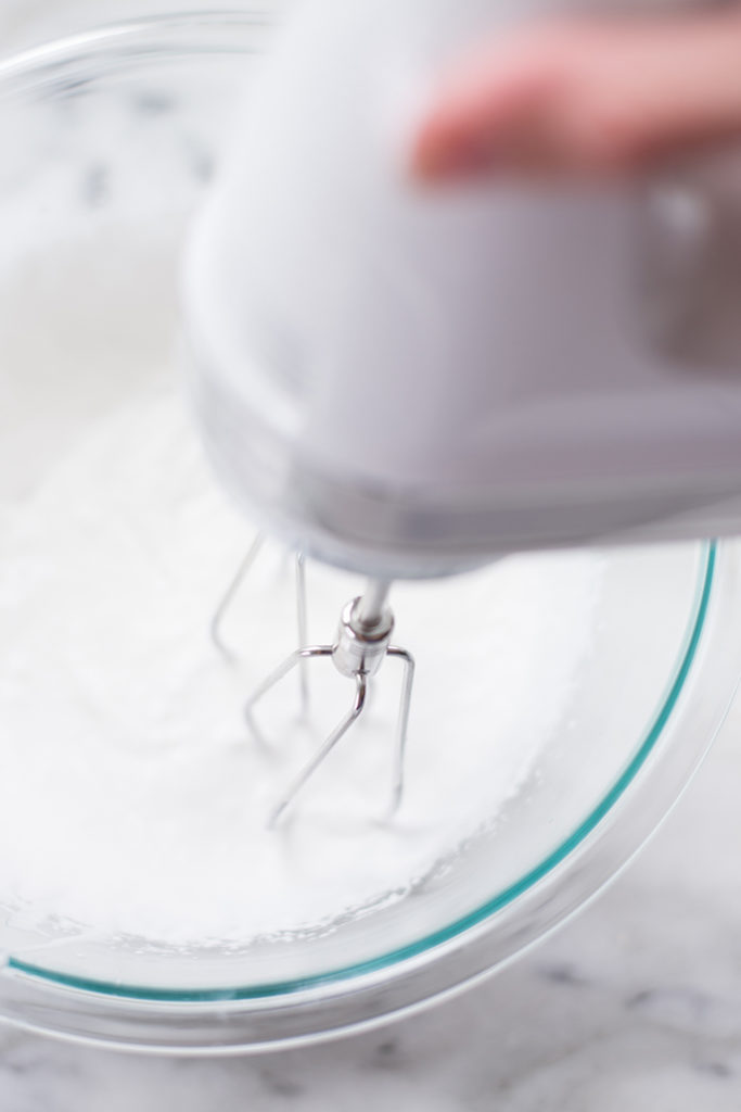Overhead view of a hand mixer whipping up the coconut milk, sea salt, pure vanilla, and pure maple syrup into keto whipped cream.