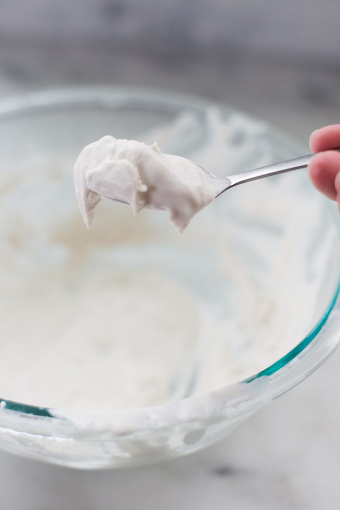View of a bowl of 4-ingredient keto whipped cream with a serving spoon full of cream, ready to be used.