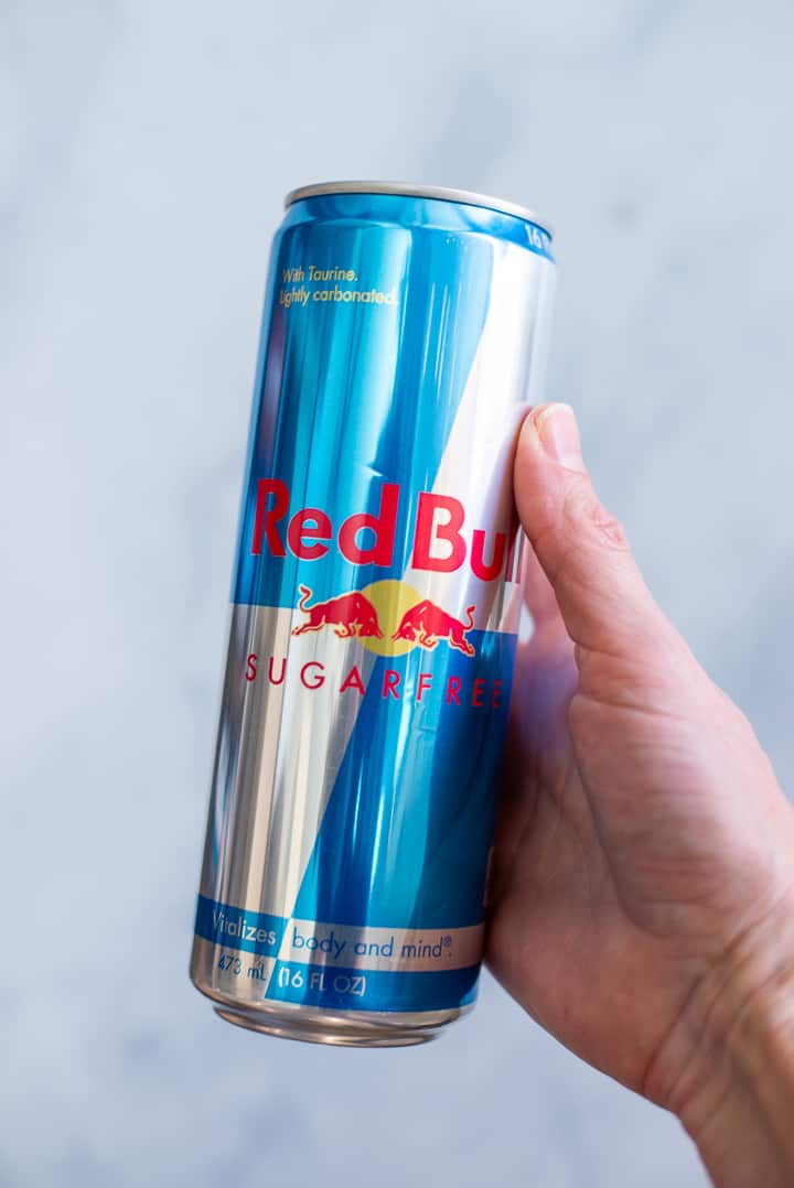 Close up side image of a hand holding a can of Red Bull Energy Drink.