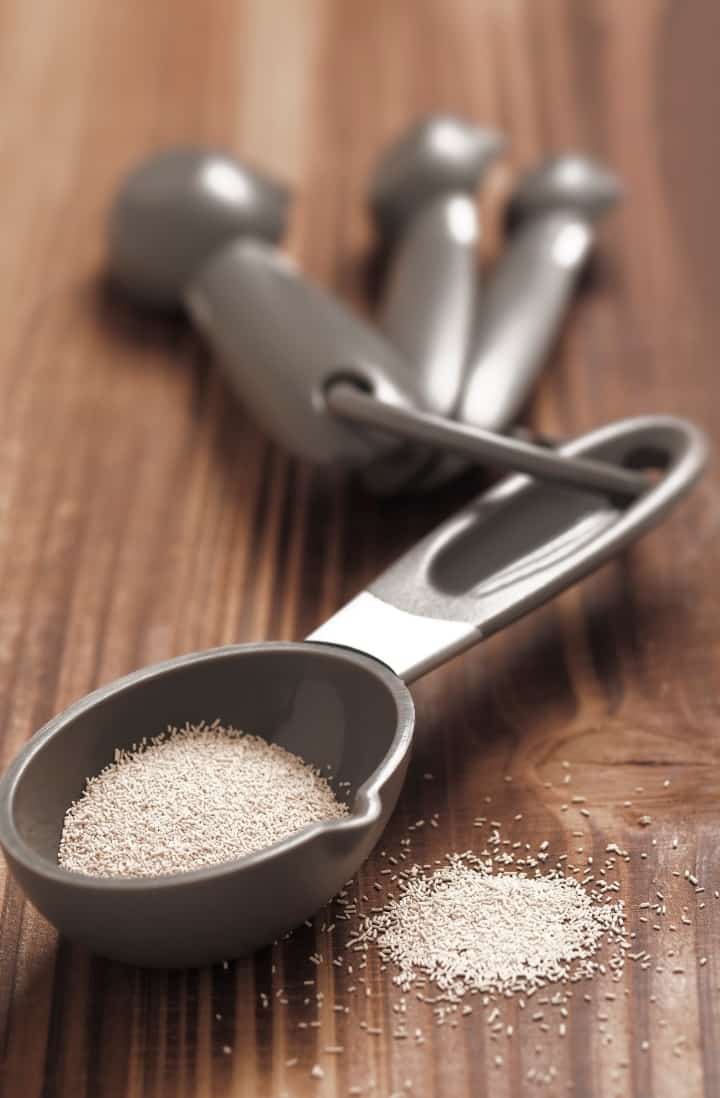 Close up image of a set of measuring spoons, one containing dry yeast.