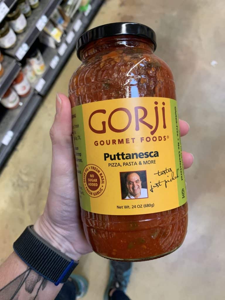 Close up image of a hand holding a large jar of Gorgi pasta sauce.