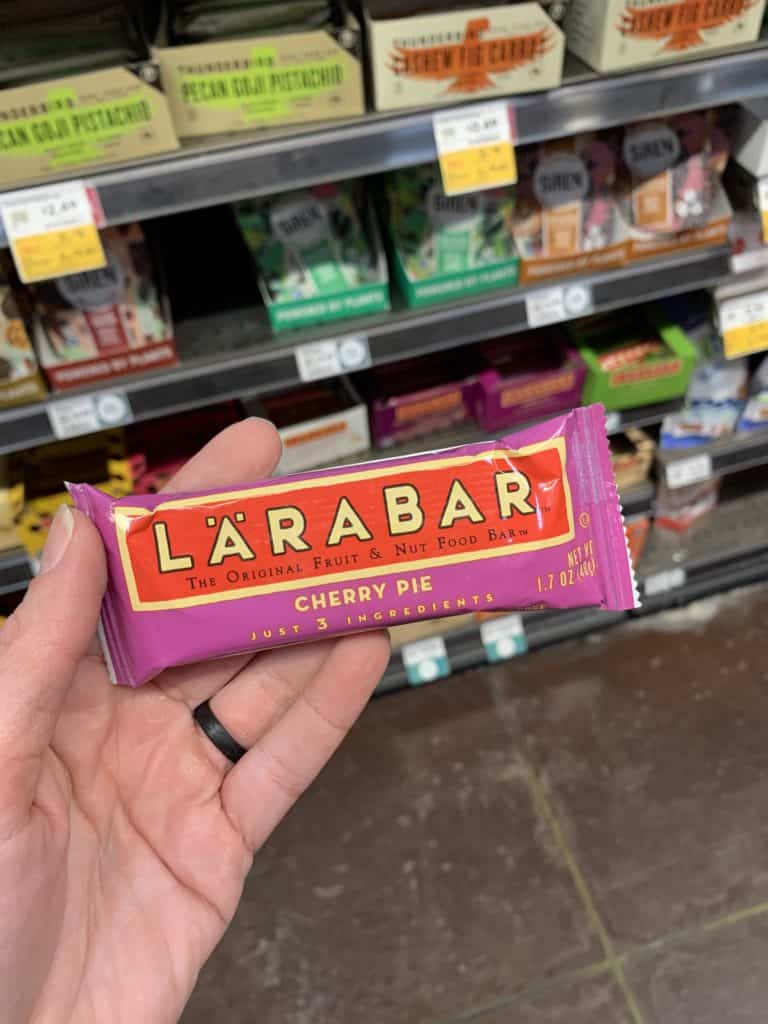Close up image of a hand holding the Larabar Protein Bar.