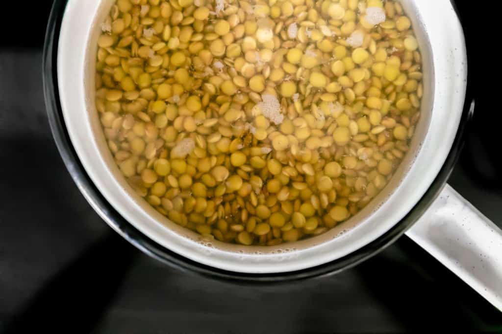 Overhead view of a saucepan filled with water and lentils ready to cook.