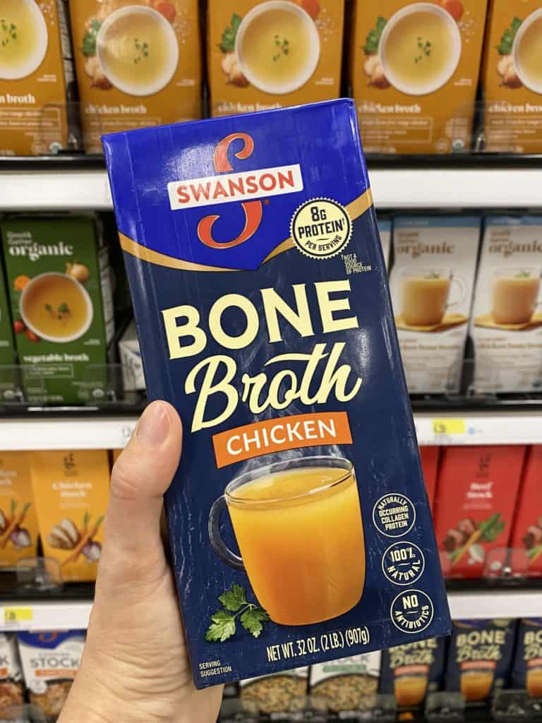 swanson bone broth being held in a grocery store