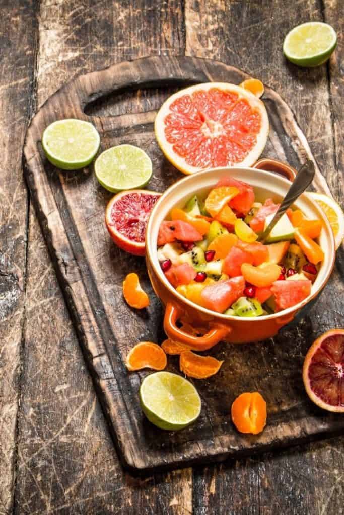 a mixed fruit bowl with grapefruit, lime, oranges, and kiwi