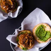 pesto and goat cheese burger plated next to another pesto and goat cheese burger
