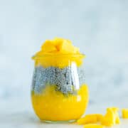 Side view of mango chia pudding, which is in a small glass jar. There are visible layers of mashed mango and the chia pudding sandwiched in between.