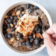 A photo of blueberry crisp overnight oats that are topped with crushed almonds and blueberries.